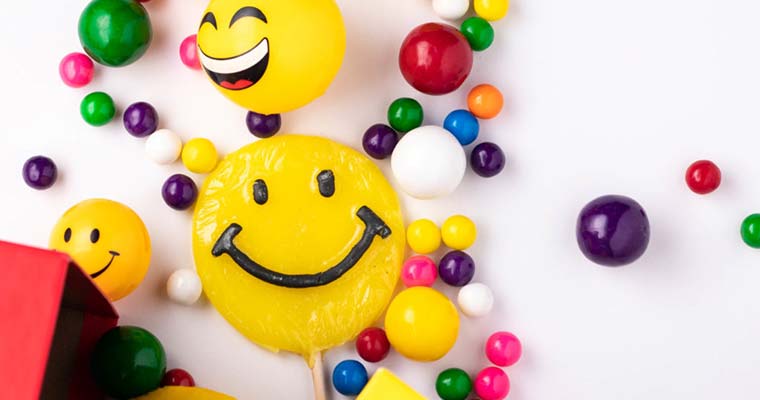 Array of colored candy, toys, and smiley face lollypops, signifying smiling with eyes during reopening.
